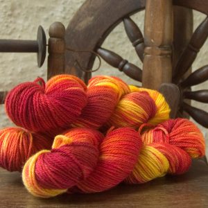 Nectarine - a mix of fruity reds over a warm peachy yellow base Bluefaced Leicester worsted weight yarn hand-dyed by Triskelion Yarn